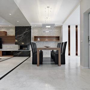 dining room interior in the foreground the wooden dining table with leather chairs next to fireplace the floor is made of marble